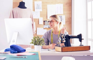 Masasında dikiş makinesi olan bir fabrikada genç ve güzel bir kız.