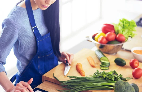 Junge Frau schneidet Gemüse in Küche zu Hause — Stockfoto