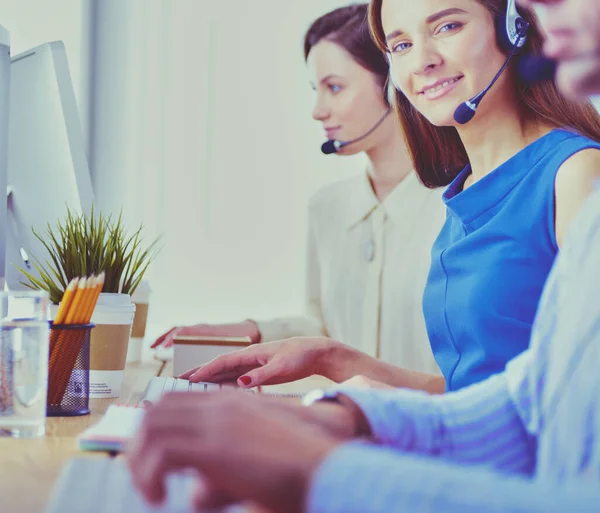 Lachende call center medewerkers zitten in de rij met hun headset — Stockfoto