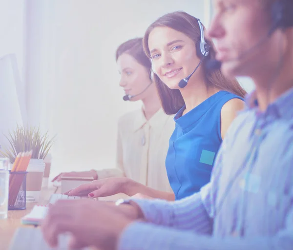 Lachende call center medewerkers zitten in de rij met hun headset — Stockfoto