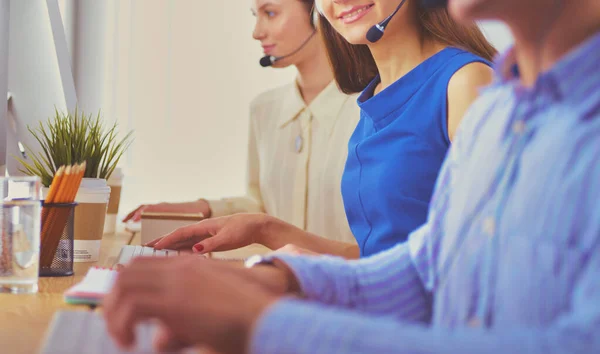 Dipendenti del call center sorridenti seduti in linea con le cuffie — Foto Stock