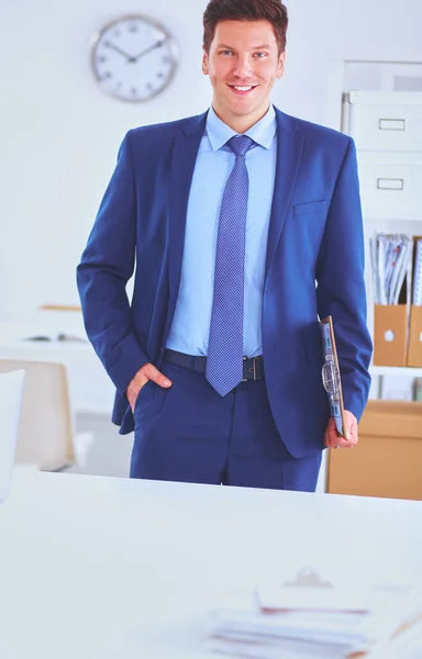Hombre de negocios o gerente de pie contra su escritorio en la oficina — Foto de Stock
