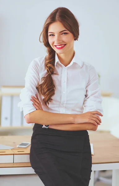 Attractive businesswoman with her arms crossed standing in off — Stock Photo, Image