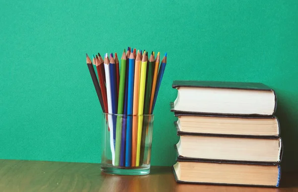 Kitaplar ve renkli kalemler yeşil zemin üzerine yığını — Stok fotoğraf
