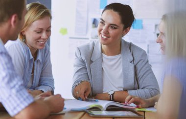 Masada kitaplarla çalışan gençler. Güzel kadınlar ve erkekler birlikte çalışıyor.
