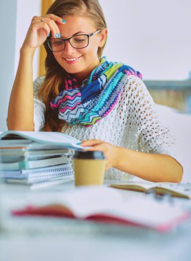 Kitapların arasında masa başında oturan genç bir kadın.