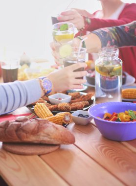 Ahşap masada otururken birlikte yemek yiyen bir grup insanın üst düzey görüntüsü. Masada yemek var. İnsanlar fast food yiyor..