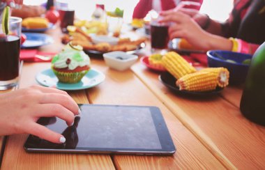 Ahşap masada otururken birlikte yemek yiyen bir grup insanın üst düzey görüntüsü. Masada yemek var. İnsanlar fast food yiyor..