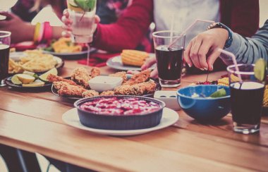 Bir grup insan ahşap masada otururken birlikte yemek yiyorlar.