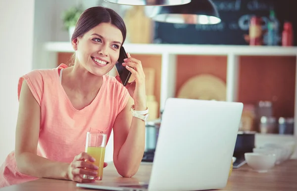 Ung kvinna i köket med bärbar dator ser recept, leende. Begreppet livsmedelsbloggare — Stockfoto