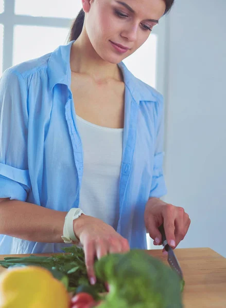 Junge Frau schneidet Gemüse in Küche zu Hause. — Stockfoto