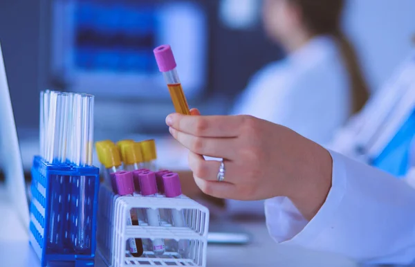Laborassistentin legt Reagenzgläser in die Halterung, Nahsicht auf die Reagenzgläser mit Tests konzentriert. — Stockfoto