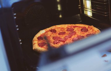 Mutlu genç bayan evde pizza pişiriyor.
