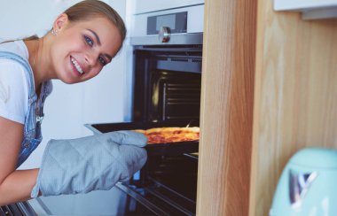 Mutlu genç bayan evde pizza pişiriyor.