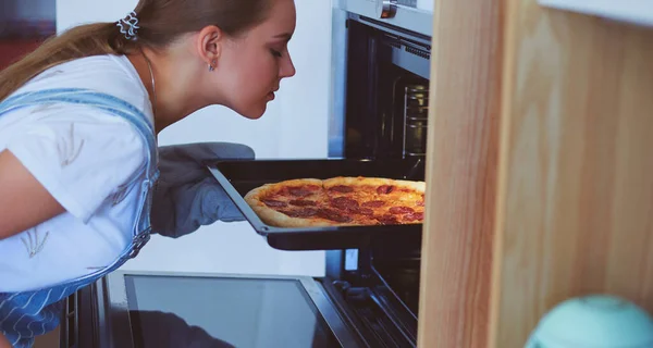 Ευτυχισμένη νεαρή γυναίκα μαγειρεύει πίτσα στο σπίτι — Φωτογραφία Αρχείου