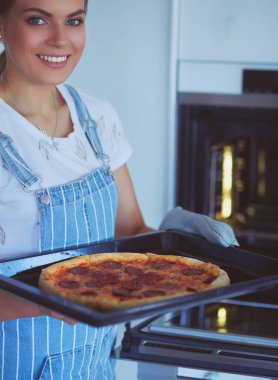 Mutlu genç bayan evde pizza pişiriyor.