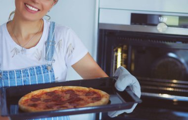 Mutlu genç bayan evde pizza pişiriyor.