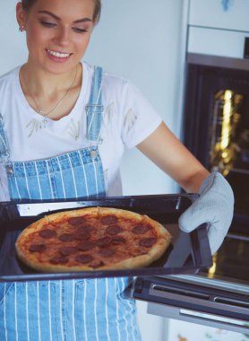 Mutlu genç bayan evde pizza pişiriyor.