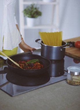 Mutfakta yemek hazırlayan genç bir kadın.