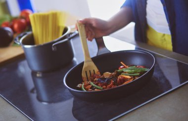 Mutfakta yemek hazırlayan genç bir kadın.