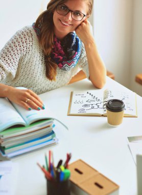 Kitapların arasında masa başında oturan genç bir kadın.