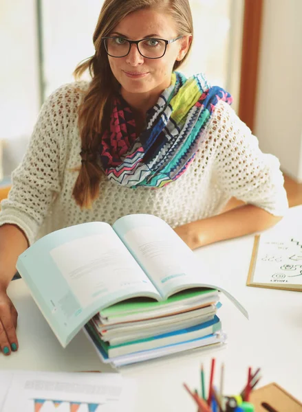 Una joven sentada en un escritorio entre libros. Estudiante — Foto de Stock