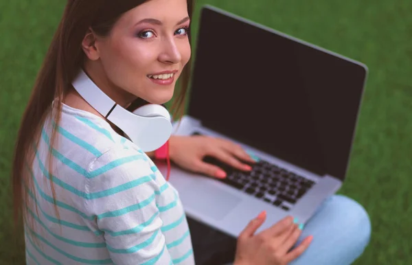 Jeune femme avec ordinateur portable assis sur l'herbe verte — Photo