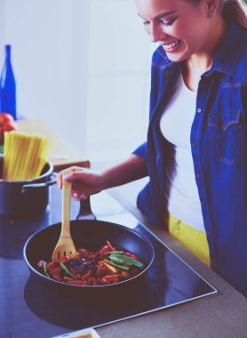 Mutfakta yemek hazırlayan genç bir kadın.