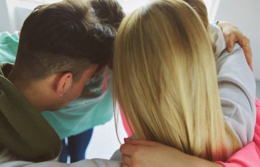 Mutlu gülümseyen arkadaşlar, bir grup genç insan ayakta ve kucaklaşıyorlar.