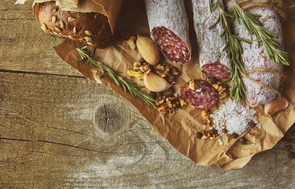 Ιταλικό σαλάμι με θαλασσινό αλάτι, δενδρολίβανο, σκόρδο και ξηρούς καρπούς σε χαρτί. Ρουστίκ στυλ. Άνω όψη. — Φωτογραφία Αρχείου
