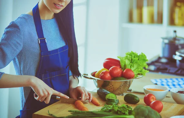 Νεαρή γυναίκα κοπής λαχανικών στην κουζίνα στο σπίτι — Φωτογραφία Αρχείου