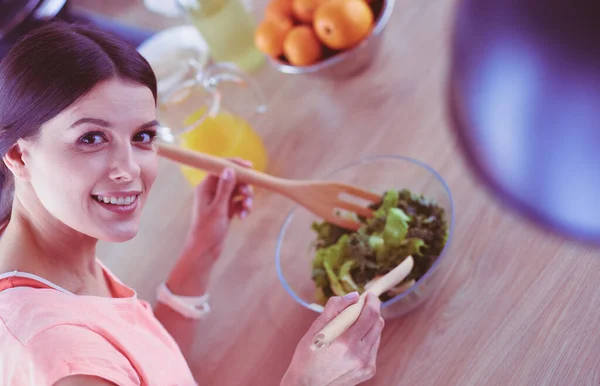 Sorrindo jovem mulher misturando salada fresca na cozinha. — Fotografia de Stock