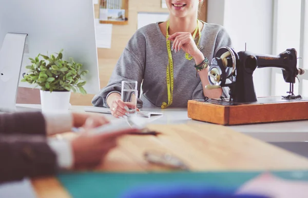 Neue modische Stile schaffen. Fröhliche junge Frau näht, während sie an ihrem Arbeitsplatz in der Modewerkstatt sitzt — Stockfoto