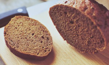 Tahta masanın üzerinde kağıda sarılı bir somun ekmek..