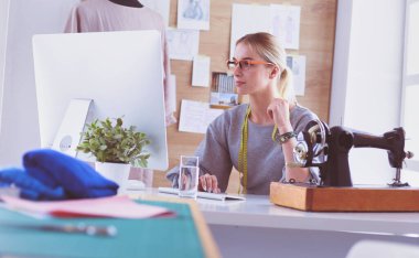 Masasında dikiş makinesi olan bir fabrikada genç ve güzel bir kız.