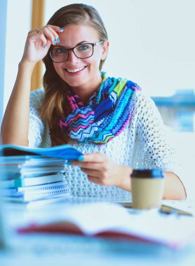 Kitapların arasında masa başında oturan genç bir kadın.