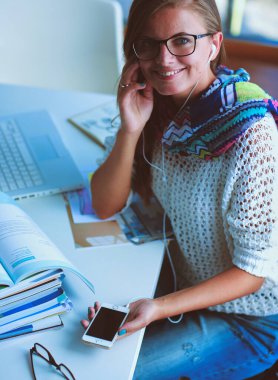 Kitapların arasında masa başında oturan genç bir kadın.