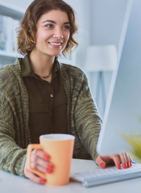 Öğrenci evdeki bir masada dizüstü bilgisayarla çalışıyor ve öğreniyor.