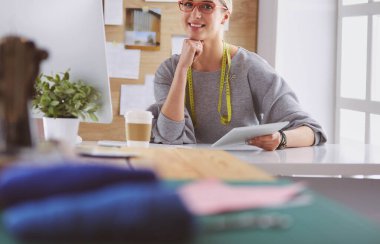 Masasında dikiş makinesi olan bir fabrikada genç ve güzel bir kız.
