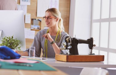 Masasında dikiş makinesi olan bir fabrikada genç ve güzel bir kız.