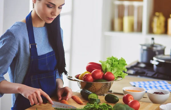 Junge Frau schneidet Gemüse in Küche zu Hause — Stockfoto