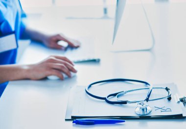 Kadın doktor masada oturuyor ve hastanede dizüstü bilgisayarla çalışıyor..