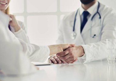 Doktor ofiste erkek bir hastayla el sıkışıyor..