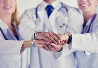 Doktorlar ve hemşireler tıbbi bir ekipte el ele tutuşuyorlar..