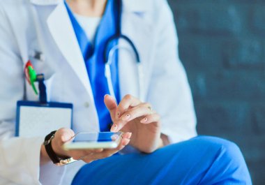 Genç bayan doktor telefonunuzla oturuyor. Kadın doktorlar