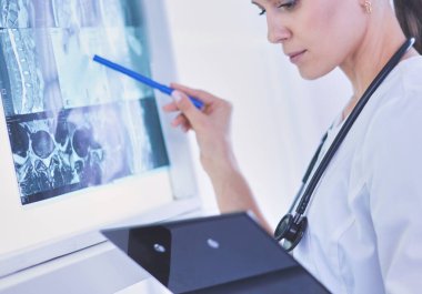 Stetoskop lu genç gülümseyen kadın doktor doktor ofisinde röntgeni işaret ediyor