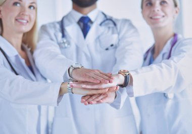 Doktorlar ve hemşireler tıbbi bir ekipte el ele tutuşuyorlar..