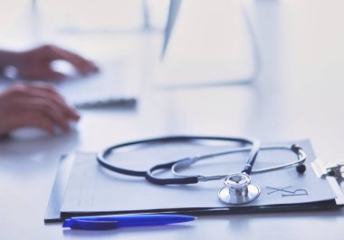 Stetoskop yakın plan dizüstü bilgisayarda yazan kadın doktorun yanında duruyor.