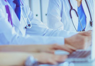 Parlak bir hastane odasında meslektaşlarıyla çalışan gülümseyen bir doktor.