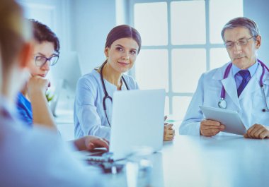 Ciddi bir tıbbi ekip parlak bir ofiste dizüstü bilgisayar kullanıyor.